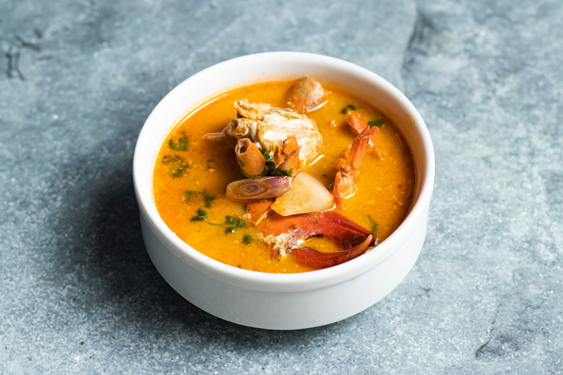 Tom Yum Seafood Soup including crab, prawn and shrimp served in broth isolated on grey background side view of thai food